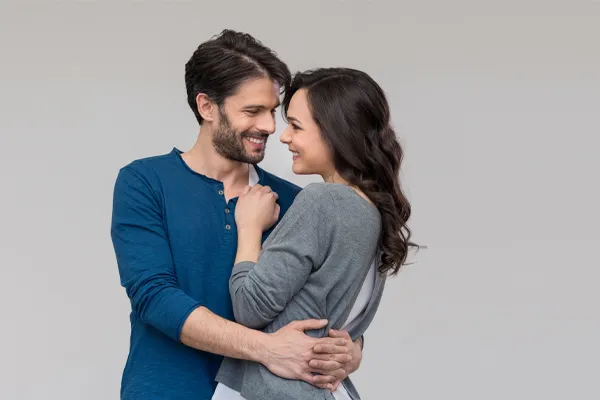 A man in a blue shirt embracing a woman in a gray shirt smiles due to his successful erectile dysfunction care from Tanya Zboril, NP of TBT Medical in Regina.