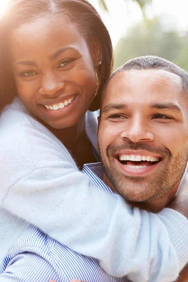 A woman riding on a man's back, both smiling due to help with erectile dysfunction from Tanya Zboril, NP of TBT Medical in Regina.
