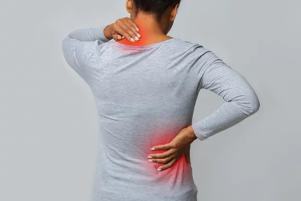Fibromyalgia-Clinic An image from behind of a woman suffering from Fibromyalgia holding her hands on her neck and lower back. Get fibromyalgia care from Tanya Zboril, NP of TBT Medical in Regina.