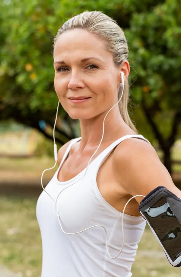 A fit middle aged woman wearing earphones and a tank top smiles after a run. Get insulin resistance treatment from Tanya Zboril, NP of TBT Medical in Regina.