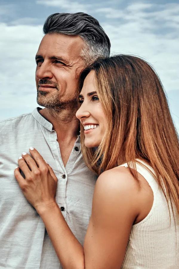 A healthy middle-aged couple look out onto the ocean. Get Medical Genetic Testing from Tanya Zboril, NP of TBT Medical in Regina.