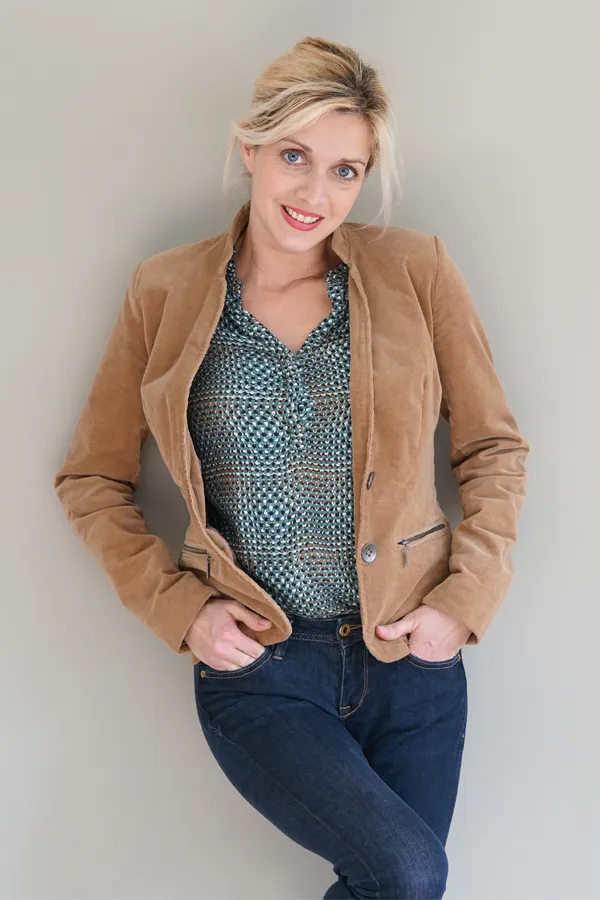 Metabolic-Syndrome-Treatment A smiling blonde woman in a tan leather jacket leans against a gray wall. Schedule metabolic syndrome from Tanya Zboril, NP of TBT Medical in Regina.