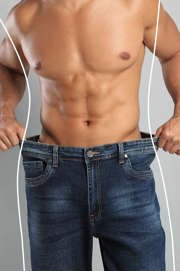 Semaglutide-Weight-Loss-Treatment A strong shirtless man in jeans holds the waistlines of his too-big jeans to show the success of semaglutide weight loss from Tanya Zboril, NP of TBT Medical in Regina.